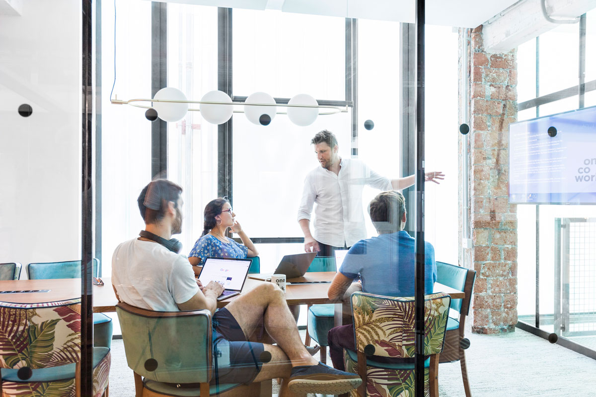Scott Mackin leading a team meeting in one of the meeting rooms at OneCoWork Catedral